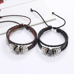 Détail de bracelets en cuir tressé avec charms tête de mort et fermeture réglable