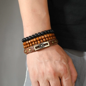 Detail view of men vintage leather wristband set with bronze cross plaque and wooden beads