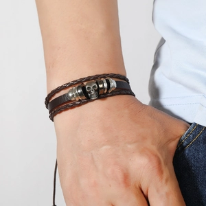 Détail d'un bracelet multicouche en cuir pour homme avec charme crâne en argent