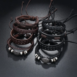 Detail of multi-layer braided leather bracelets with vintage metal sun charms
