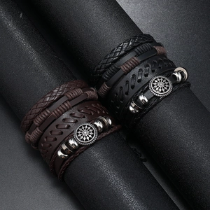 Close-up of black and brown multilayer braided leather bracelets with punk metal charms