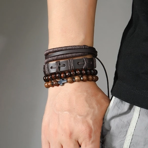 Macro detail of men's multi-layer leather bracelets with a metal cross charm