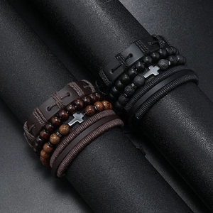 Detail of layered leather bracelets featuring a metal cross and mixed natural beads