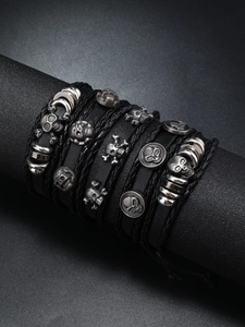 Detailed view of punk leather bracelet set with silver skull charms on a black display stand