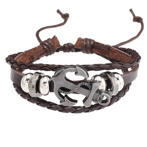 Détail d'un bracelet multicouche en cuir avec breloque ancre et texture tressée