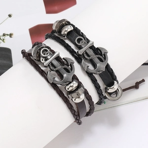 Gros plan de bracelets multicouches en cuir tressé avec pendentifs ancre en métal vieilli