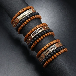 Close-up of multilayer men's leather bracelet set with cross and God Bless metal charms