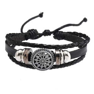 Détail d'un bracelet multicouche en cuir tressé avec breloque soleil vintage et perles