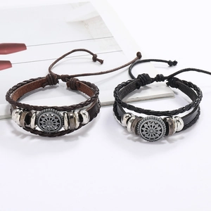 Détail de bracelets en cuir tressé vintage avec breloques tournesol et nœuds coulissants