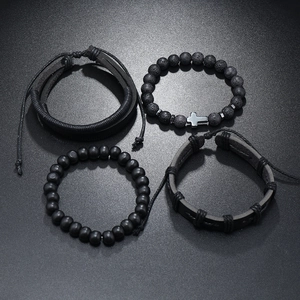 Detail of four-piece men's black bracelet set with cross pendant and braided leather