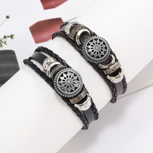 Détail de bracelets en cuir multicouches avec pendentif soleil rétro sur support blanc