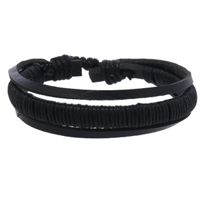 Detail of multi-layer black leather woven bracelet set with rustic braided cord textures