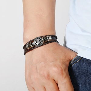 Détail d'un bracelet multicouche en cuir pour homme avec des breloques en métal argenté