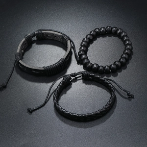 Détail du lot de trois bracelets noirs en cuir tressé avec perles en bois et cordon ciré