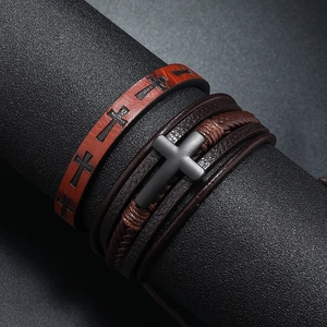 Detail of vintage men's cross bracelet set featuring woven leather on a black stand