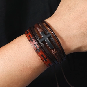 Close-up of layered leather bracelet with black cross charm and embossed cross patterns