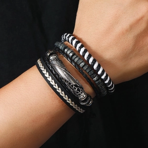 Macro view of multi-layer leather bracelets with wooden beads and feather metal charms