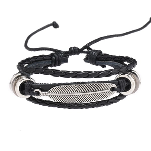 Détail d'un bracelet multicouche en cuir avec pendentif plume argenté et perles en métal