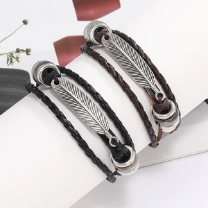 Détails rapprochés de bracelets en cuir tressé avec charms en plume métallique