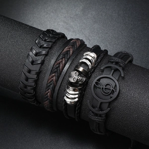 Set of 4 men's punk leather bracelets with skull and anchor charms on a black display