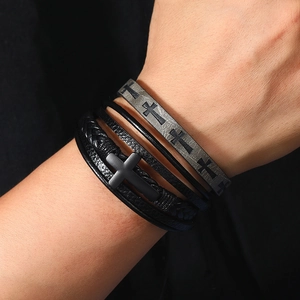 Macro shot of men's multi-layer braided leather bracelets with a matte metal cross charm