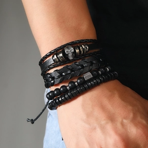 Close-up of men's multi-layer black bracelet set featuring leather, beads and skull charm