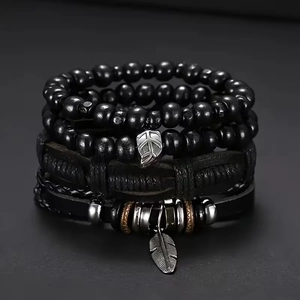 Detail showing multi-layer leather bracelets with black wooden beads and feather charms