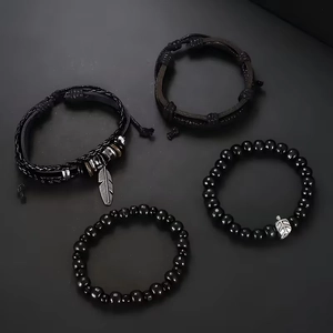 Detail of four-piece black leather beaded bracelet set with feather and leaf pendants