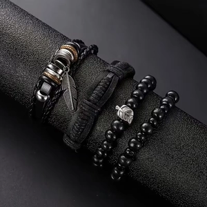 Detail of four-piece men's leather bracelet set featuring feather and leaf pendants