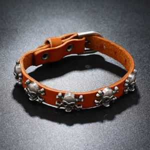 Detail of brown leather punk bracelet featuring skull studs and metal buckle closure