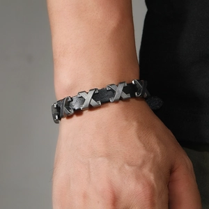 Nahaufnahme des schwarzen Lederarmbands für Herren mit Vintage-Metall-X-Bolzen