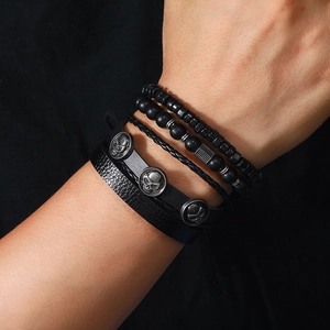 Close-up of four-piece layered black men's bracelets with skull charm and matte beads