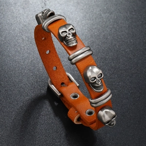 Detail of punk leather bracelet with silver skull charms and metal buckle closure