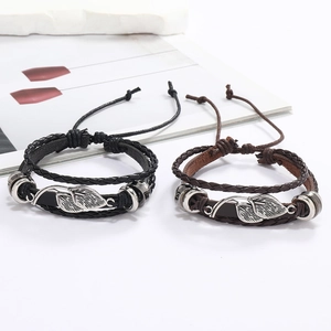 Détail de bracelets en cuir tressé multicouches avec breloques de feuilles en métal argenté