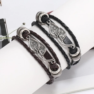 Détail de bracelets en cuir multicouches avec breloques feuilles argentées et cordons tressés