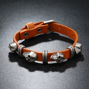 Close-up of bright orange punk leather bracelet with silver skull charm and buckle strap