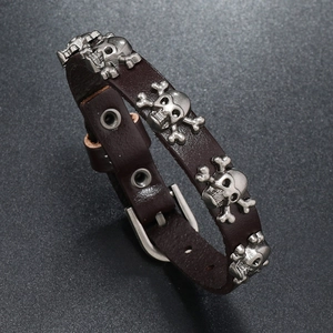 Detail of dark brown punk leather bracelet with silver skull charms and metal buckle