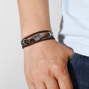 Détail d'un bracelet en cuir marron à plusieurs rangs avec un pendentif feuille argenté