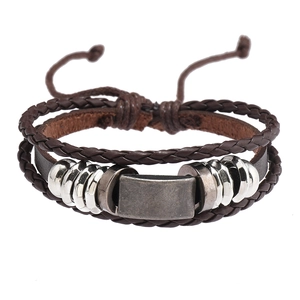 Détail d'un bracelet en cuir multicouche avec cordon ajustable et breloques en métal