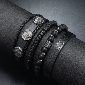 Detail of four men's punk black leather and beaded bracelets featuring silver skulls