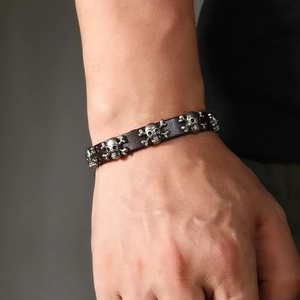 Detailed view of punk leather bracelet featuring silver metal skulls and adjustable buckle