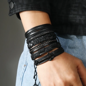 Macro detail of men's layered leather bracelet with studs and metal axe charm