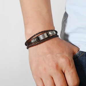 Détail du bracelet multicouche en cuir marron avec plaque en métal vintage et perles