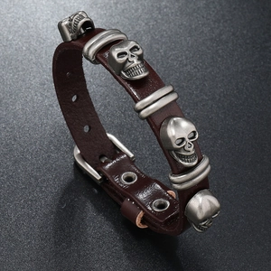Detail of punk leather bracelet showing skull charms and adjustable metal buckle