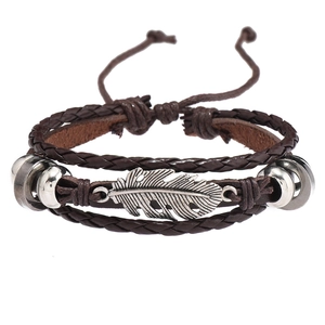 Détail d'un bracelet en cuir multicouche marron foncé avec un pendentif plume en argent