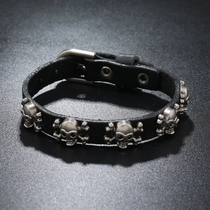 Detail of black punk leather bracelet featuring silver skull studs and adjustable buckle