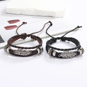 Détail de bracelets en cuir faits main avec breloques plumes en alliage d'argent vintage