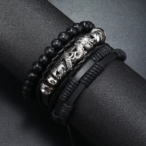Macro detail of men's multilayered black leather bracelet with embossed dragon metal charm