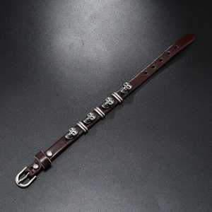 Detailed close-up of dark brown leather punk bracelet with vintage silver skull studs