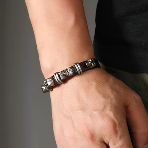 Detail view of men's leather bracelet with vintage silver skulls and punk metal rivets